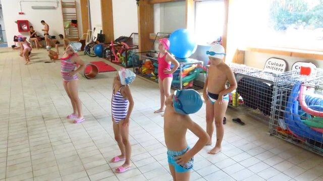 Copii inotand in grup cu instructori certificati